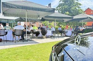 Teilnehmende verbringen den Nachmittag an gedeckten Tischen auf der Terrasse des Golfclubs.