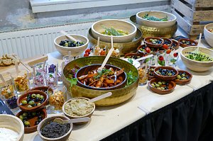 Ein reichhaltiges Buffet, das mit verschiedenen kleinen Vorspeisen, Salaten, eingelegtem Gemüse und Dip-Schalen samt kleinen Beschriftungstafeln angerichtet ist.