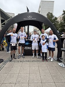Man sieht das Autohaus Peter Firmenlauf-Team vor dem Lauf, vor dem schwarzen Pavillon. Alle haben die gleichen weißen Sport-Shirts an, lachen in die Kamera, manche machen den Daumen hoch.